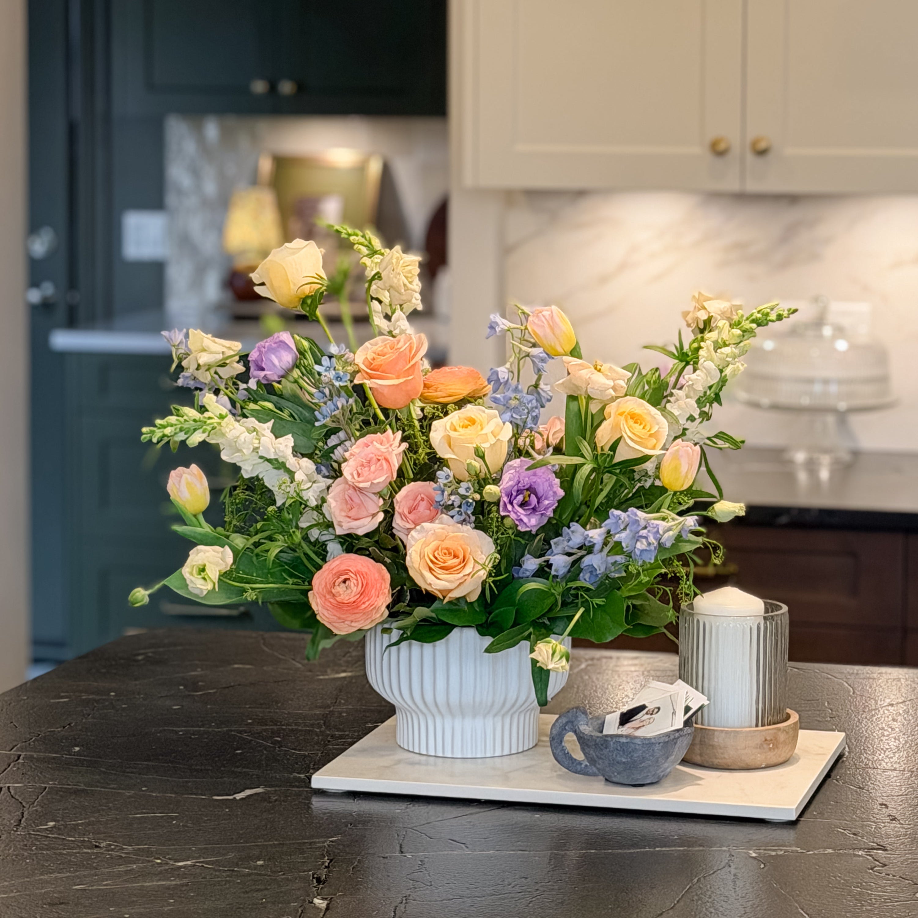 Floral arrangement on a kitchen counter with cabinets and appliances in the background