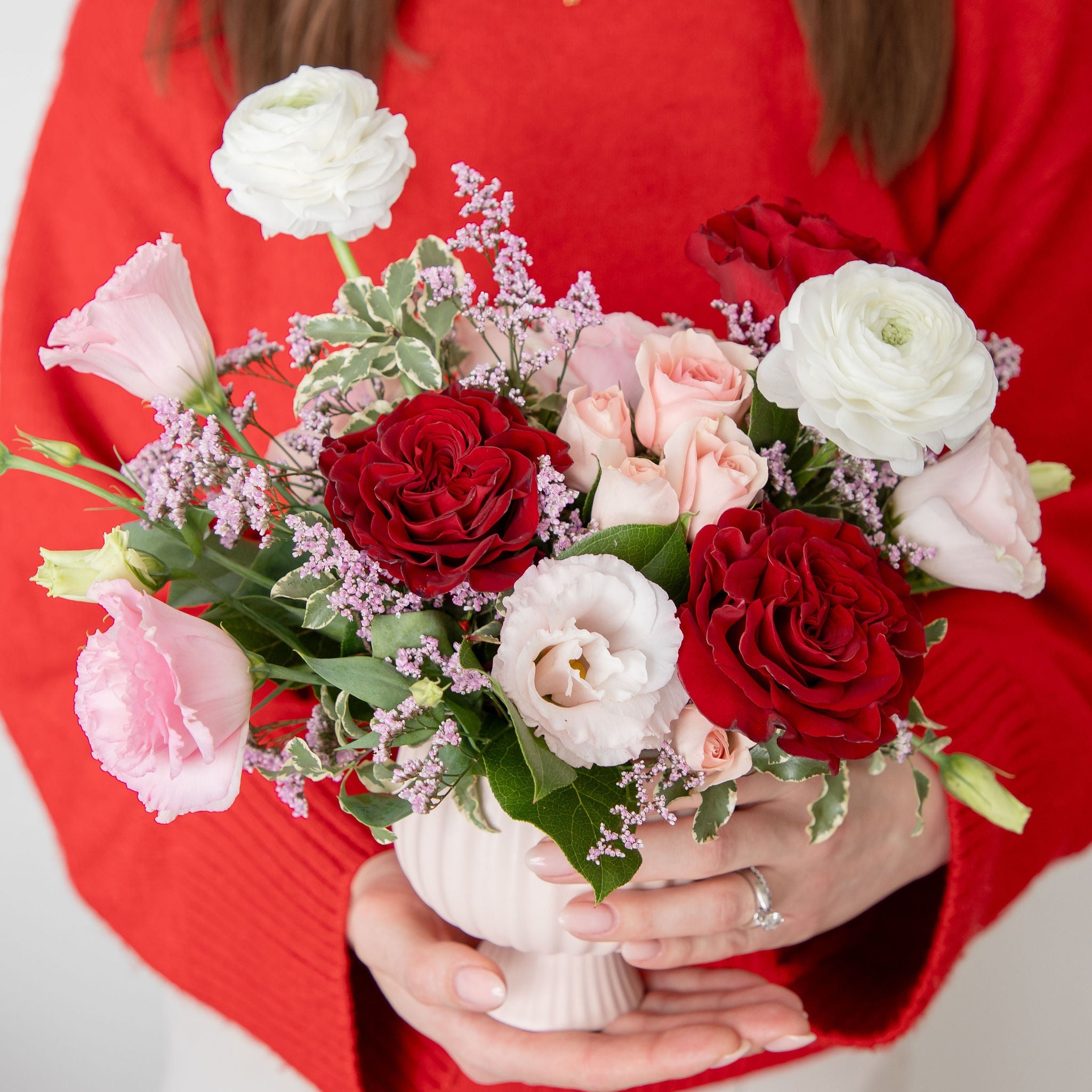 Red heart, white ranunculus, pink lisianthus, pink spray rose arrangement in a blush footed compote