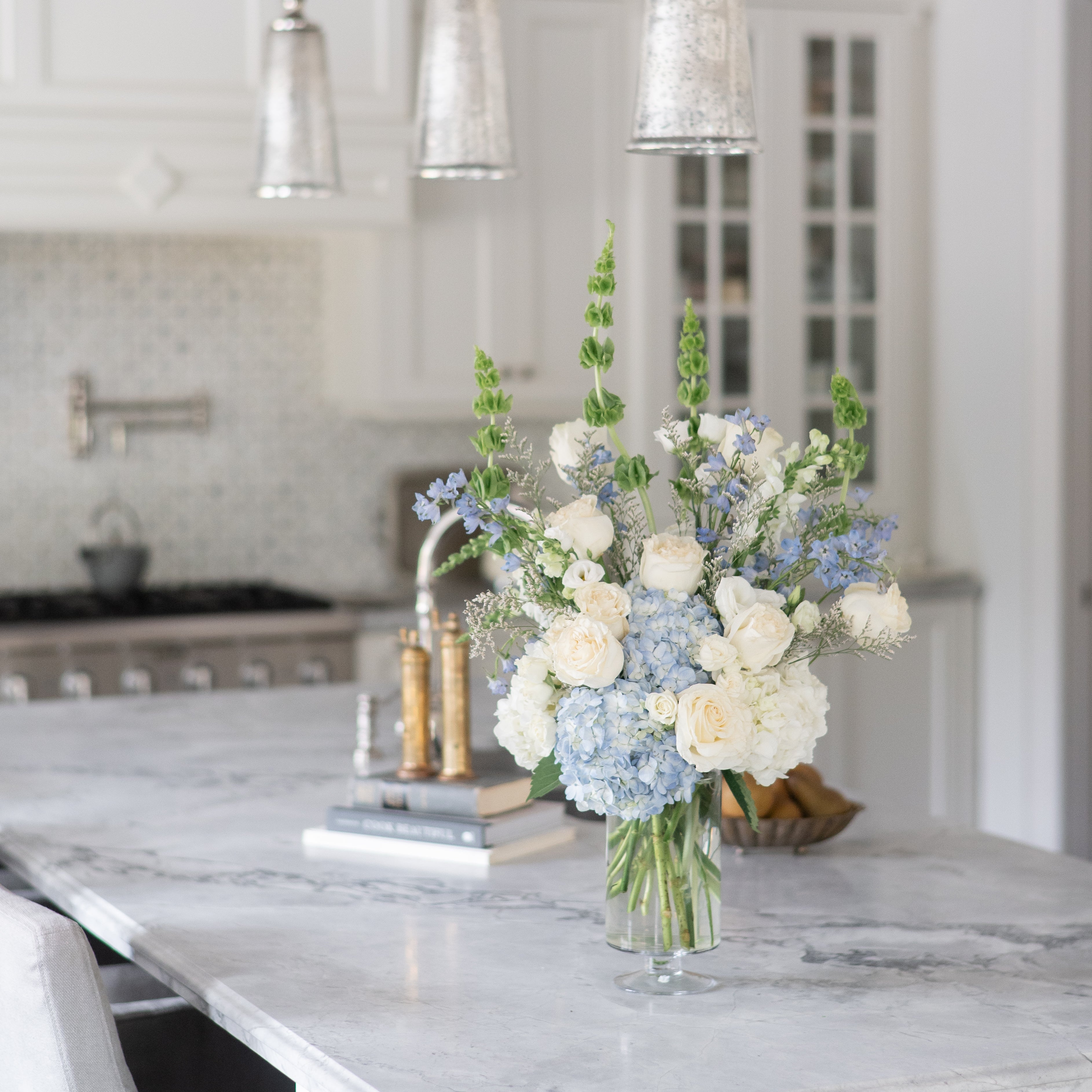 Kitchen island with a vase of blue and white sympathy flowers.