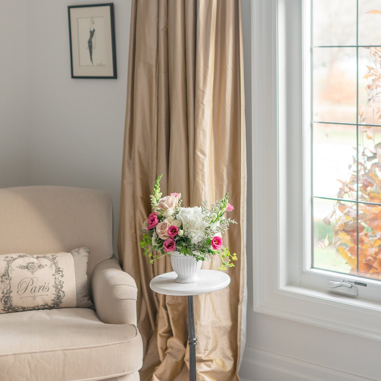 Living room with white and pink floral arrangement on a marble pedestal table.