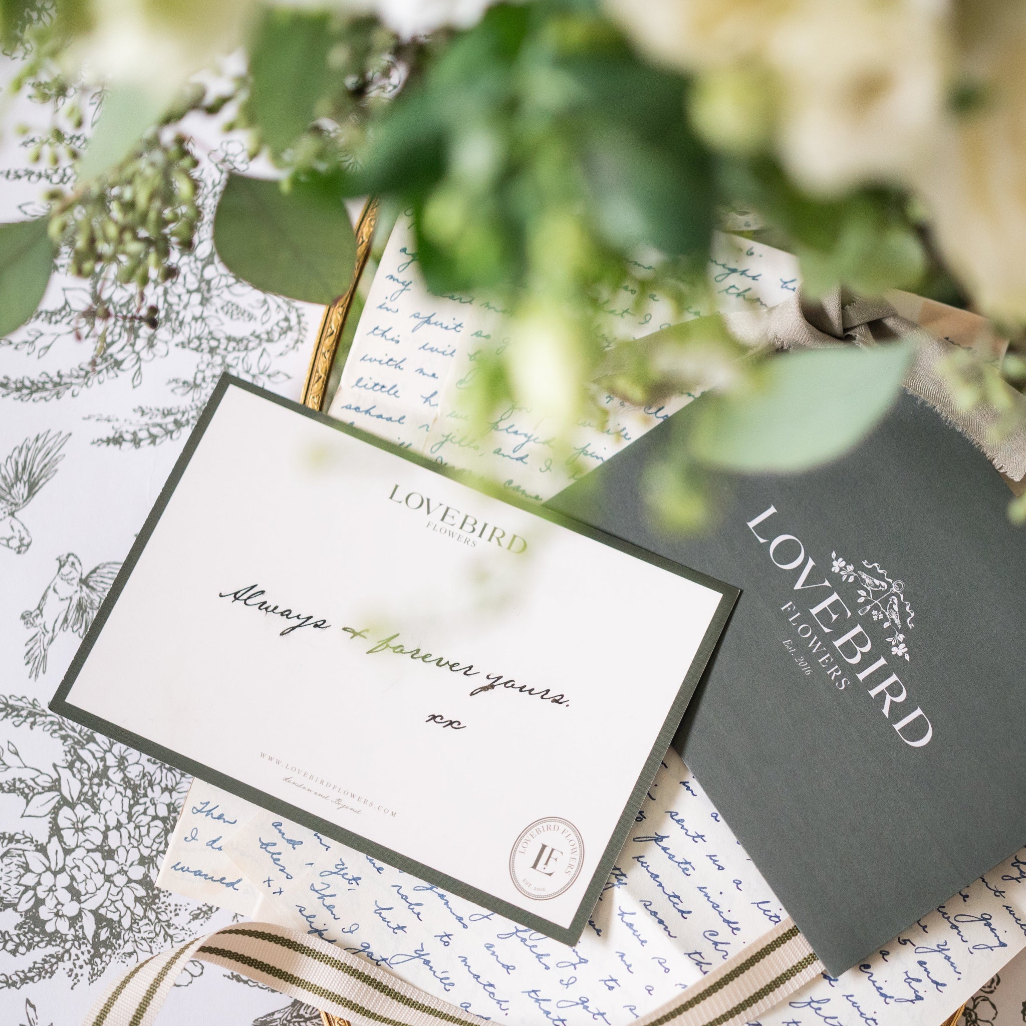 Lovebird Flowers packaging with a hand written note card on a toile background