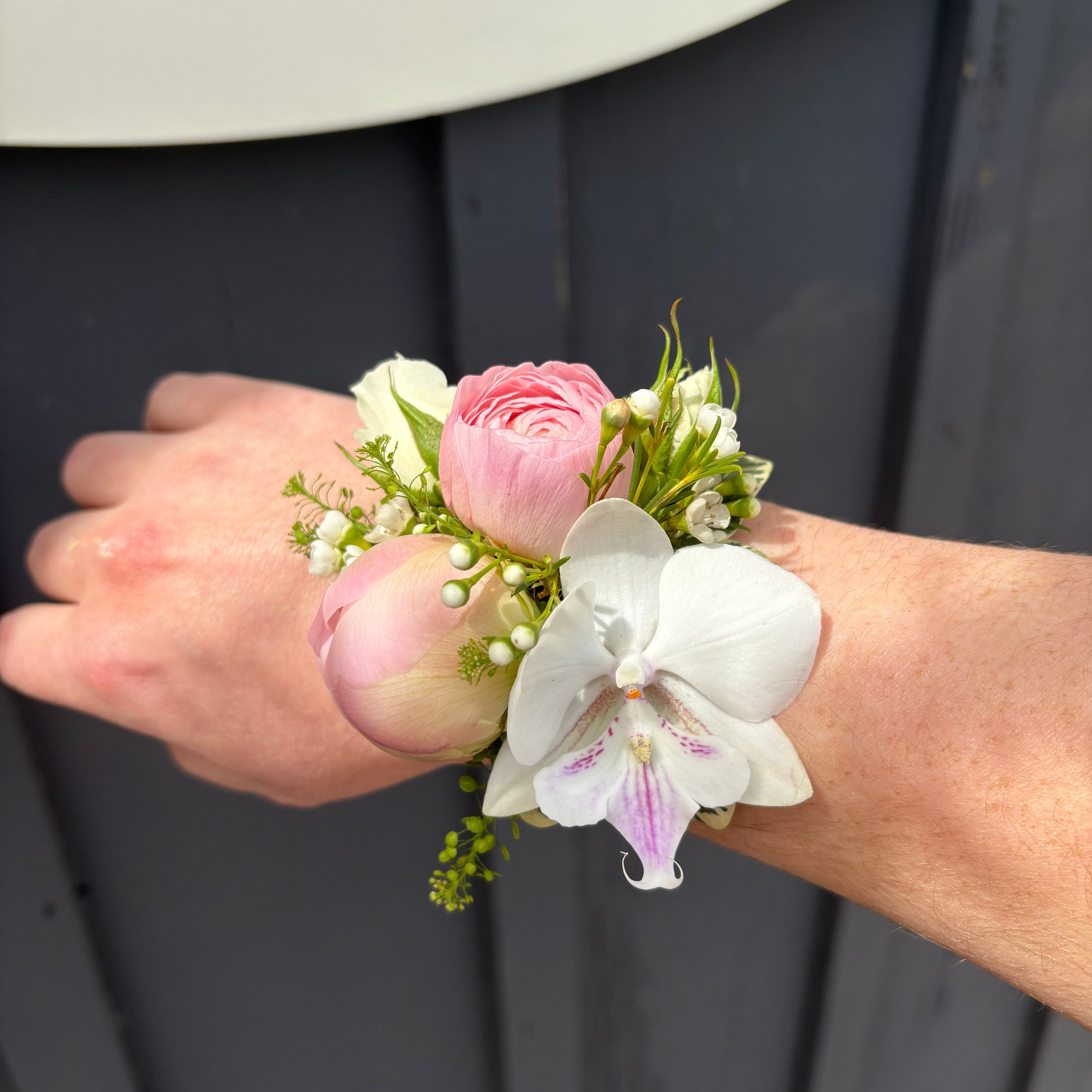 Floral wrist corsage on a person's wrist with a blurred background