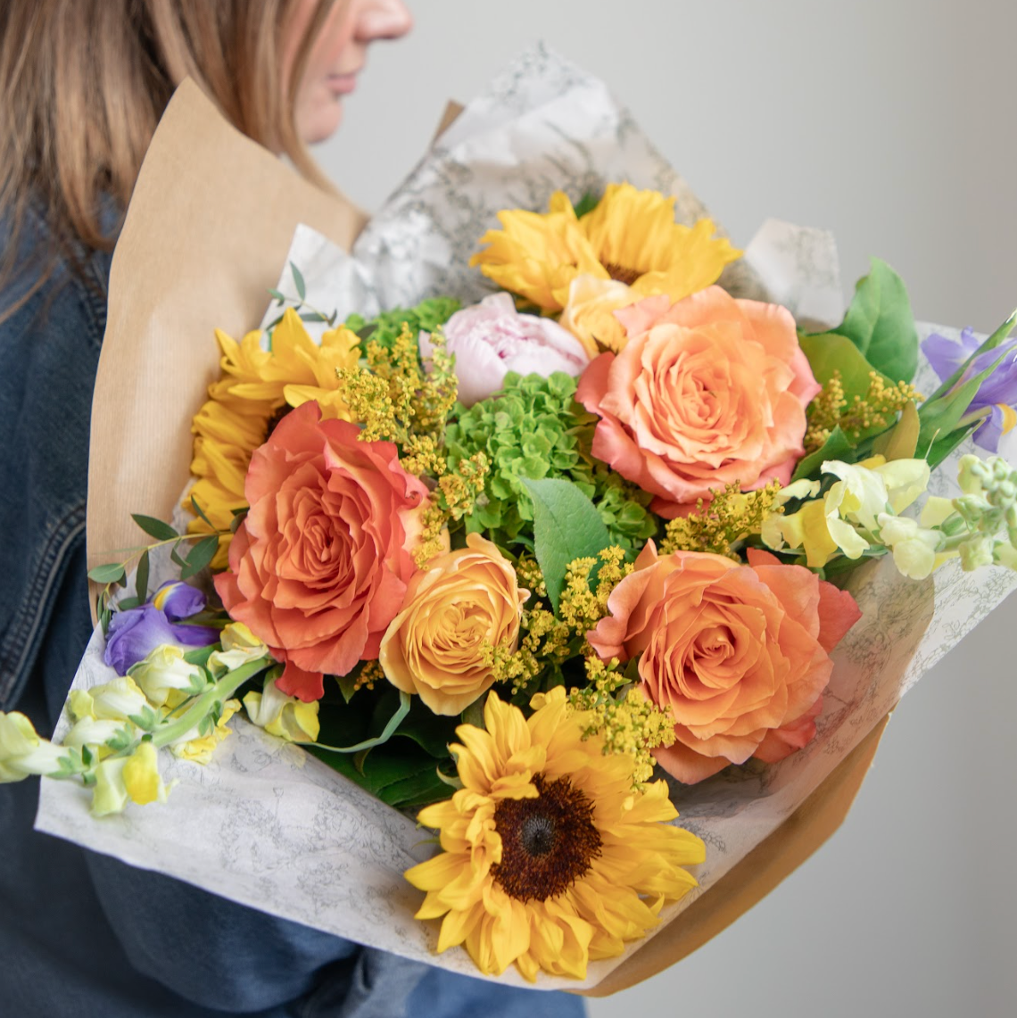Woman holding a bouquet of colorful flowers against a plain background