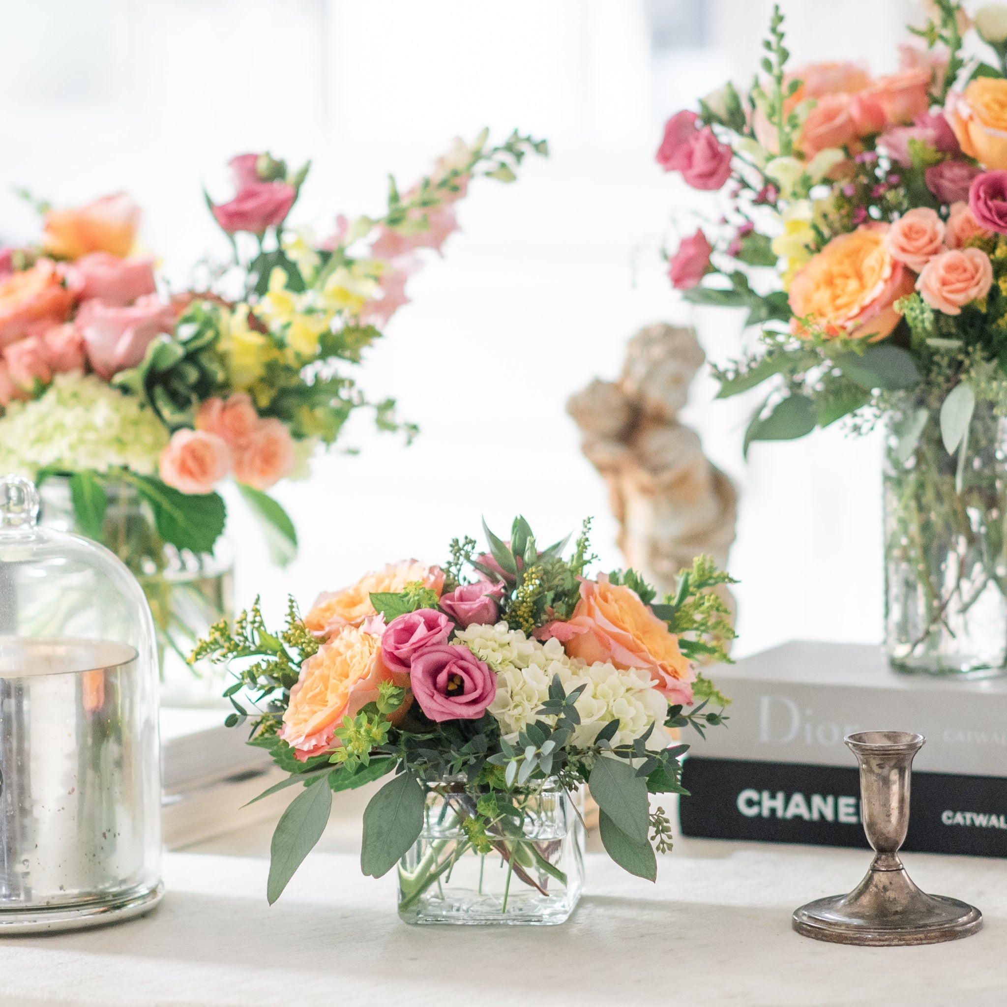 bright coloured flower arrangement trio featuring free spirit roses, snap dragons, pink lisanthus and hydrangea on white marble coffee table