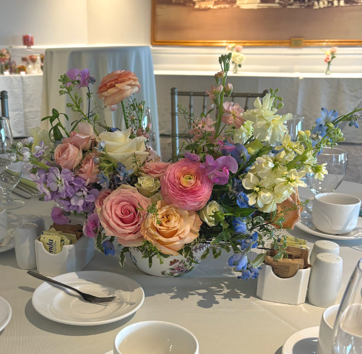 Floral arrangement on a table with plates and cups in a restaurant setting